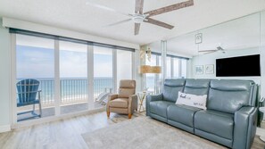 A spacious living area with a balcony overlooking the ocean, a leather sofa, and a ceiling fan. - #606 Atlantica Oceanfront 2/2 Condo. (Ponce Inlet)