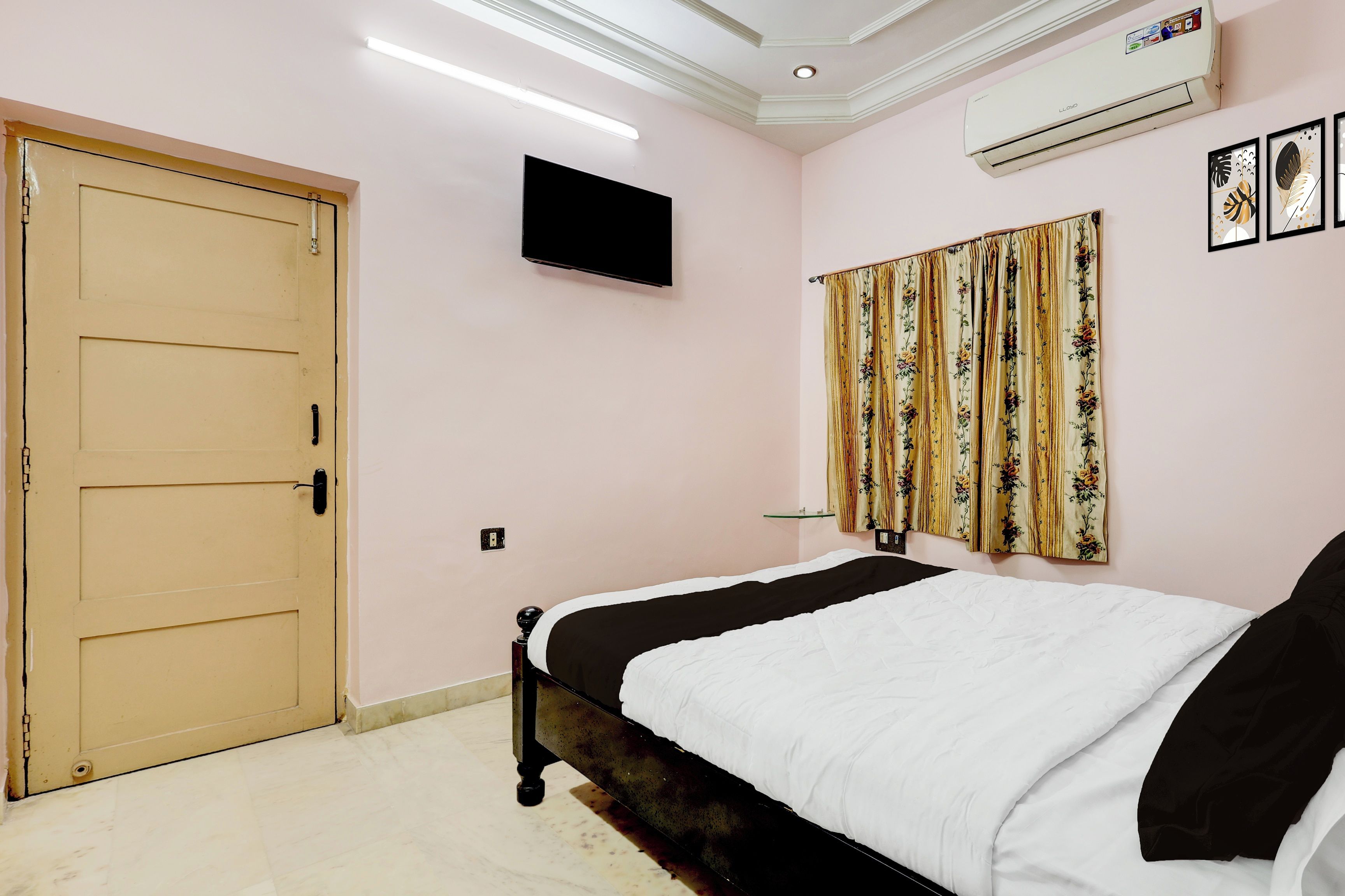 A bedroom with a bed, a television, an air conditioner, and a door.