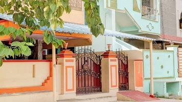 A residential building with a gated entrance, a staircase, and a small porch area.
