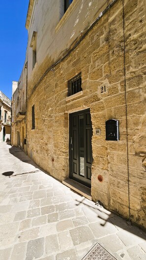 A narrow street with a stone building, a black door, and the number 21 on the wall. - Domus Sirii - Vacation Home in the Heart of Lecce's Historic Center (Lecce)