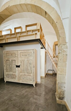 A room with a wooden staircase, a large wardrobe, and an arched ceiling. - Domus Sirii - Vacation Home in the Heart of Lecce's Historic Center (Lecce)