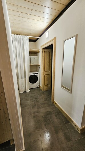 A hallway with a washing machine, a wooden door, and a mirror on the wall. - Domus Sirii - Vacation Home in the Heart of Lecce's Historic Center (Lecce)
