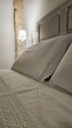 Ein Bett mit einem gemusterten Bettbezug und Kissen, ein hölzernes Kopfteil und eine Wandlampe.
