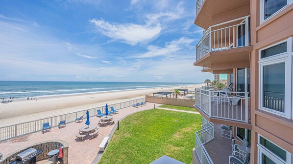 Ein Strandhotel mit Terrassenbereich, Sitzgelegenheiten im Freien und Blick auf den Strand.