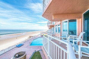 A balcony with a view of the beach, a pool, and outdoor seating. - Coastal Luxury at the Blue Surf 301 (Daytona Beach Shores)