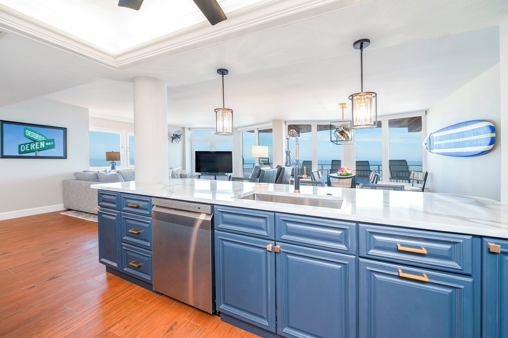 A modern kitchen with a large island, stainless steel appliances, and pendant lighting.