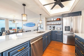 A modern kitchen with a central island, built-in appliances, and a view to the outdoors. - Coastal Luxury at the Blue Surf 301 (Daytona Beach Shores)
