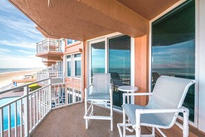 A balcony with two chairs and a table, overlooking a beach and ocean. - Coastal Luxury at the Blue Surf 301 (Daytona Beach Shores)