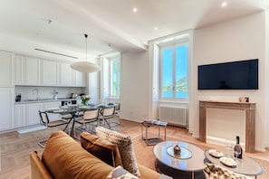 A modern living space with a kitchen, dining area, and a TV mounted on the wall. - Daydream in Villa Pozzi (Villa Pozzi)