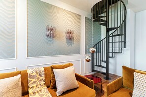 A modern interior with a spiral staircase, a patterned wall, and a sofa with patterned cushions. - Daydream in Villa Pozzi (Villa Pozzi)