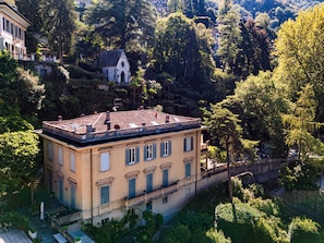 A two-story building with a flat roof, surrounded by lush greenery and trees. - Daydream in Villa Pozzi (Villa Pozzi)
