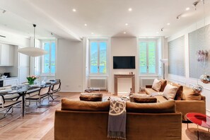 A modern living room with a sofa, a dining table set for four, a fireplace, and a television. - Daydream in Villa Pozzi (Villa Pozzi)