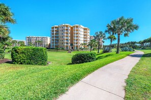 A multi-story hotel with a central courtyard, surrounded by well-maintained lawns and palm trees. - C103 Links North in Ponce Inlet, FL (Ponce Inlet)