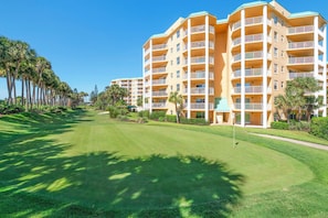 Un hotel de varios pisos con balcones y un césped bien cuidado.