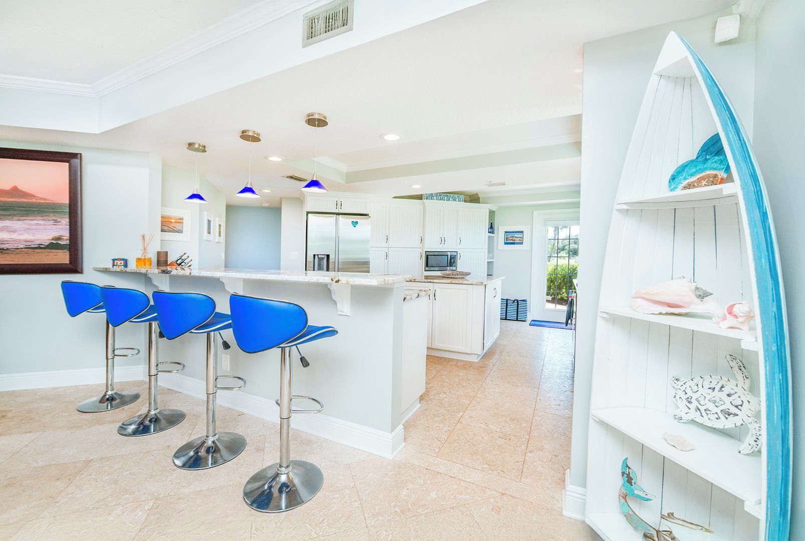 A modern kitchen with white cabinets, a central island, and blue bar stools.