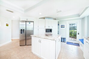 A kitchen with white cabinetry, a stainless steel refrigerator, a microwave, and a marble countertop. - C103 Links North in Ponce Inlet, FL (Ponce Inlet)