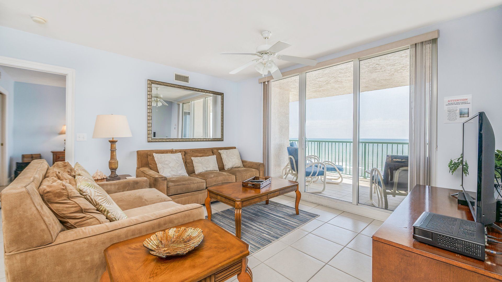 Un salon avec un canapé, une table basse et un téléviseur. Il y a un balcon avec vue.