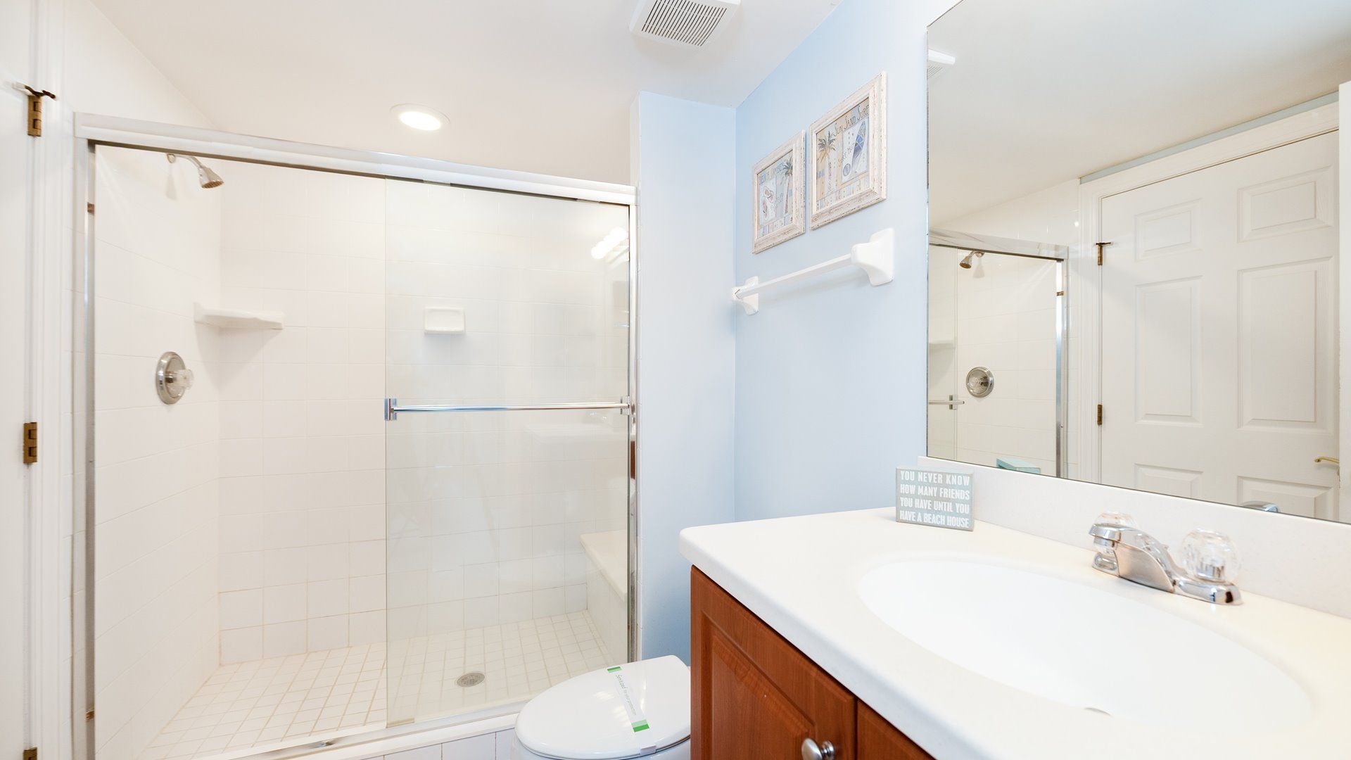 A bathroom with a glass-enclosed shower, a white sink, and a toilet.