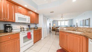 A modern kitchen with wooden cabinets, a white stove, and granite countertops. - Dimucci Twin Towers 1503 (Daytona Beach Shores)