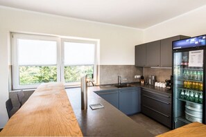 Eine moderne Küche mit einem großen Fenster, einer integrierten Spüle und einem mit Getränken gefüllten Kühlschrank.