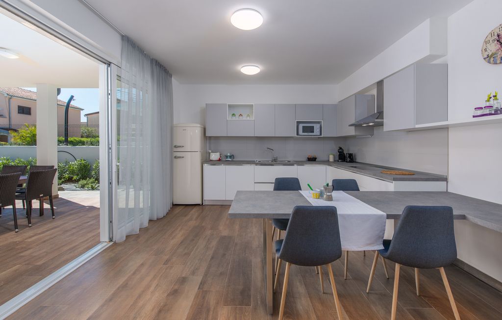 Una cocina moderna con comedor, que incluye una mesa grande y sillas, un refrigerador y un microondas.