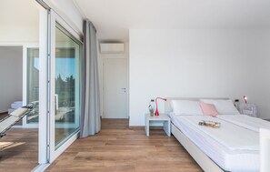 A modern bedroom with a bed, bedside table, and a view through a glass door.