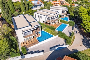 Ein moderner Wohnkomplex mit mehreren Häusern, einem Gemeinschaftspool und einem gepflegten Garten.