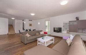 A modern living room with a sofa, coffee table, and television. - Villas Paliska (Premantura)