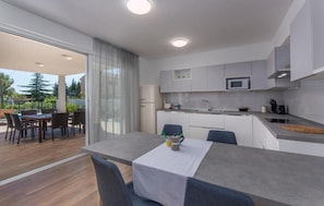 A modern kitchen with a dining area, a microwave, and a refrigerator. - Villas Paliska (Premantura)