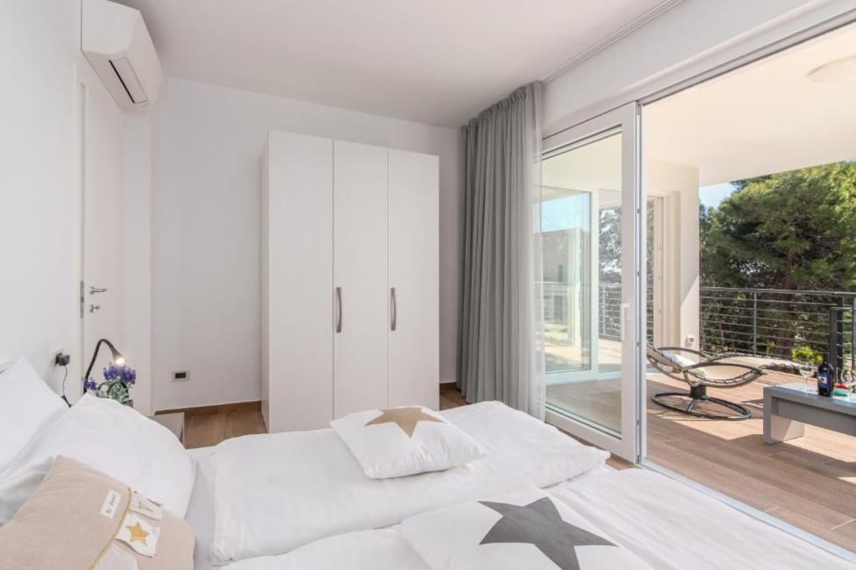 Ein modernes Schlafzimmer mit einem großen Bett, einem Kleiderschrank und einem Balkon mit Gartenmöbeln.