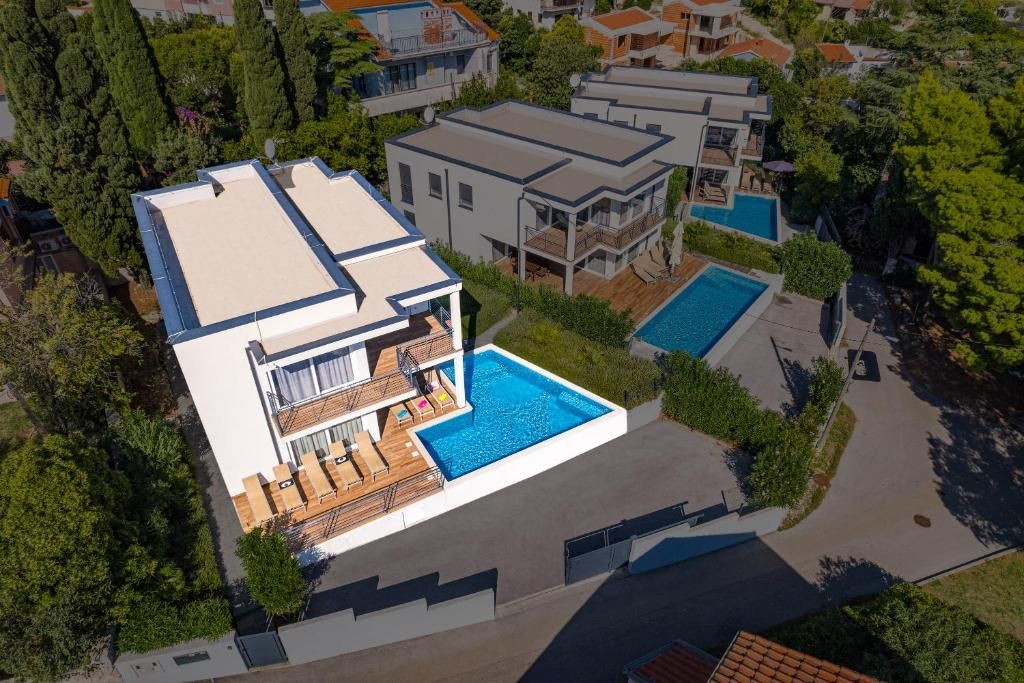 Una casa moderna de dos plantas con piscina, un porche cubierto y vistas a casas vecinas.