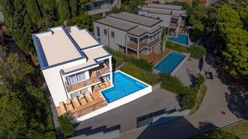 Una casa moderna de dos plantas con piscina, un porche cubierto y vistas a casas vecinas.