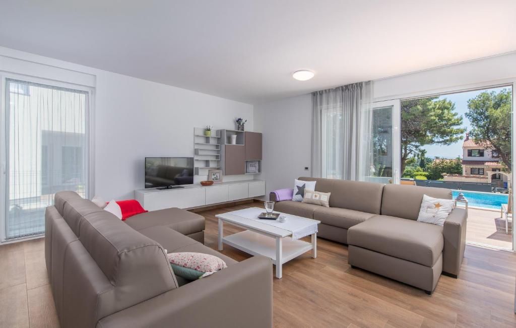 Een moderne woonkamer met een zithoek, een salontafel, een televisie en uitzicht op een zwembad.