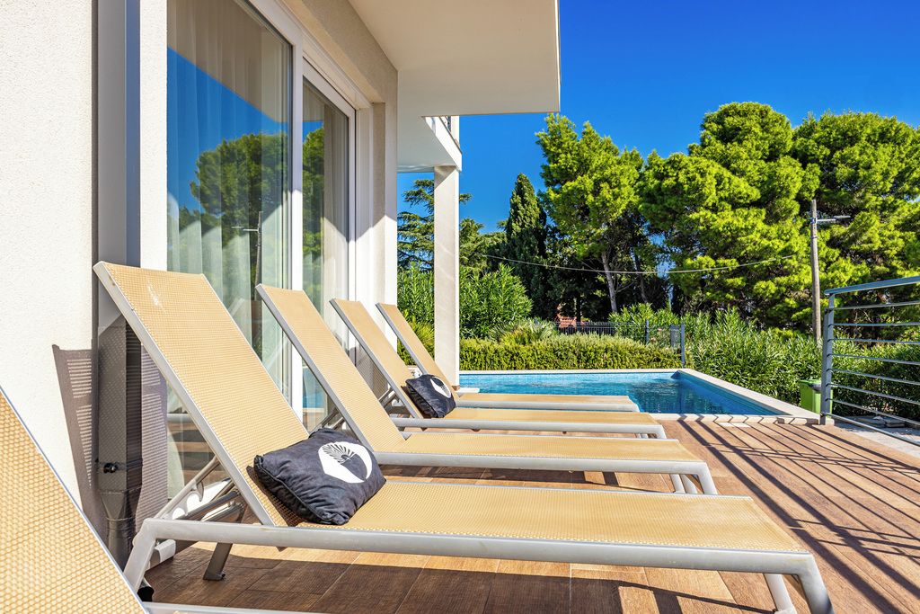 Zona de piscina con sillones de descanso y una piscina.