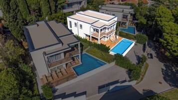 A modern two-story house with a swimming pool, a covered patio, and a garage.