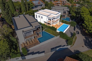 Une maison moderne à deux étages, dotée d’une piscine, d’un patio couvert et d’un garage.