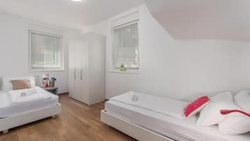 Un dormitorio con cama, mesita de noche, armario y ventana.
