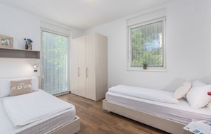 A modern bedroom with a bed, a sofa bed, a wardrobe, and a window with a view of greenery. - Villas Paliska (Premantura)