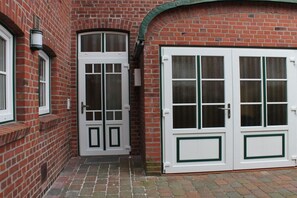 A brick building with two white doors, one with a glass panel and the other with a solid panel. - Holiday apartment with 1 bedroom (Otterndorf)