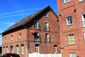 Een gebouw van rode baksteen met veel ramen en een witte schutting.
