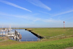 Un port de plaisance avec des bateaux amarrés, un canal et une tour rouge et blanche qui se profile au loin.