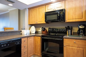 A kitchen with wooden cabinets, a microwave, a stove, and a dishwasher. - Spacious Oversized Balcony on 2nd Floor - Great Ocean Views (Daytona Beach Shores)