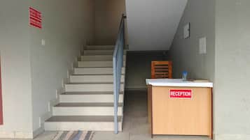 Ein Empfangsschalter mit einem Schild, eine Treppe und ein Stuhl.