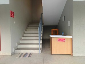 Ein Empfangsschalter mit einem Schild, eine Treppe und ein Stuhl.