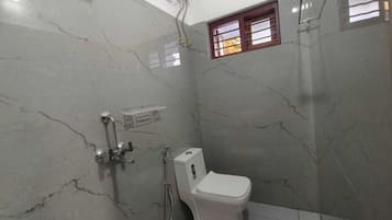 Ein Badezimmer mit Toilette, Dusche und einem Fenster mit Gitterstäben.