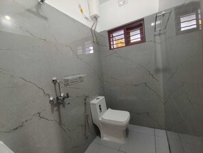 Ein Badezimmer mit Toilette, Dusche und einem Fenster mit Gitterstäben.