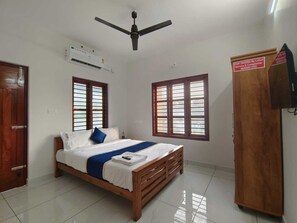 A bedroom with a bed, a wardrobe, a ceiling fan, and windows.