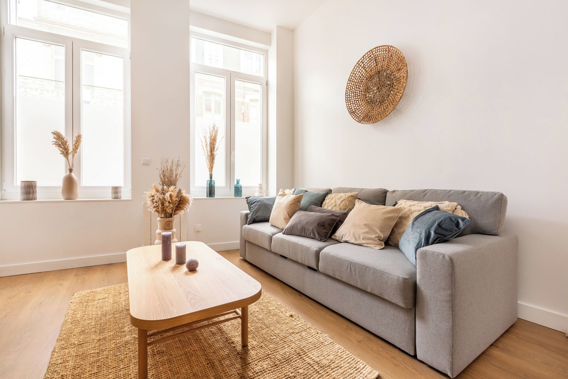 Un salon moderne avec un canapé gris, une table basse en bois et un tapis tissé.