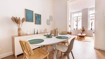 A modern dining area with a white table, green placemats, and wicker chairs.