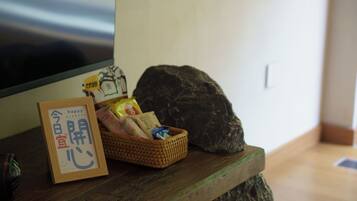 A wooden table with a framed sign, a wicker basket with snacks, and a large rock.